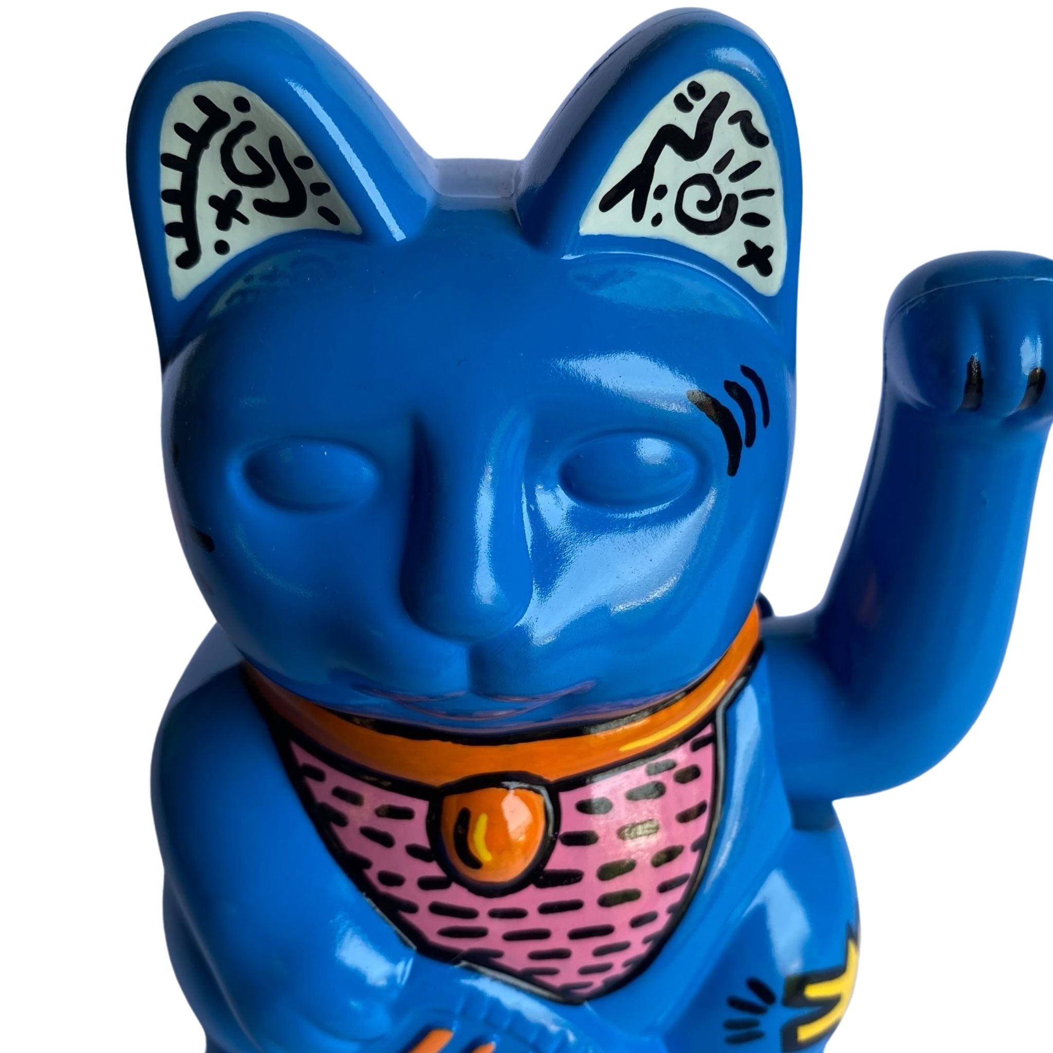 Close Up view of a Blue cat figurine with a pink belly and orange collar on a white background