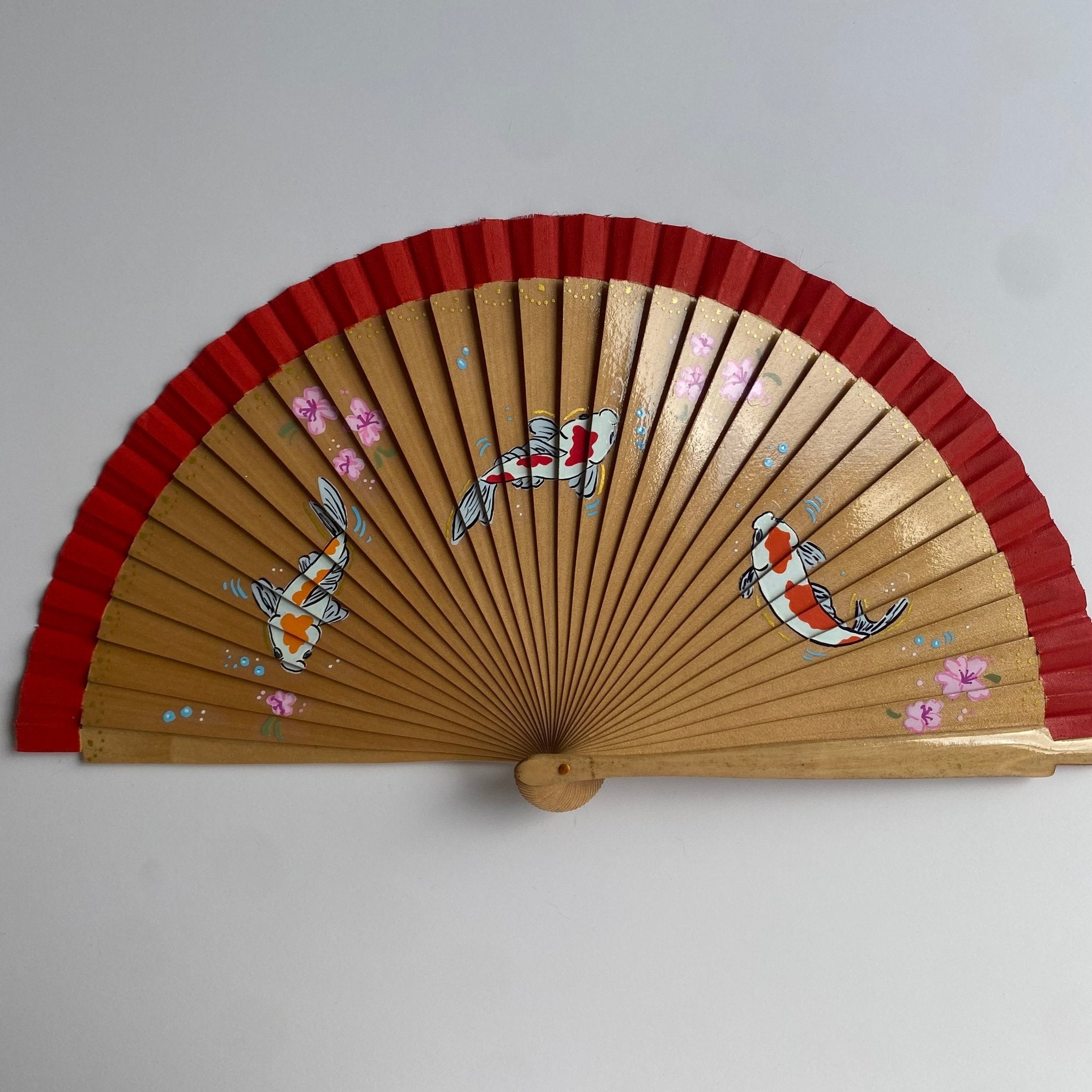 hand fan with red and gold design on a white background